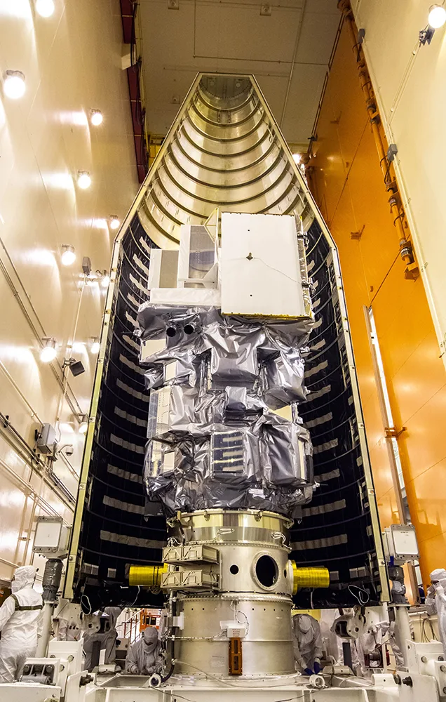 The encapsulated payload stack, wrapped in silver multi-layer insulation, standing inside an open Atlas V fairing half.