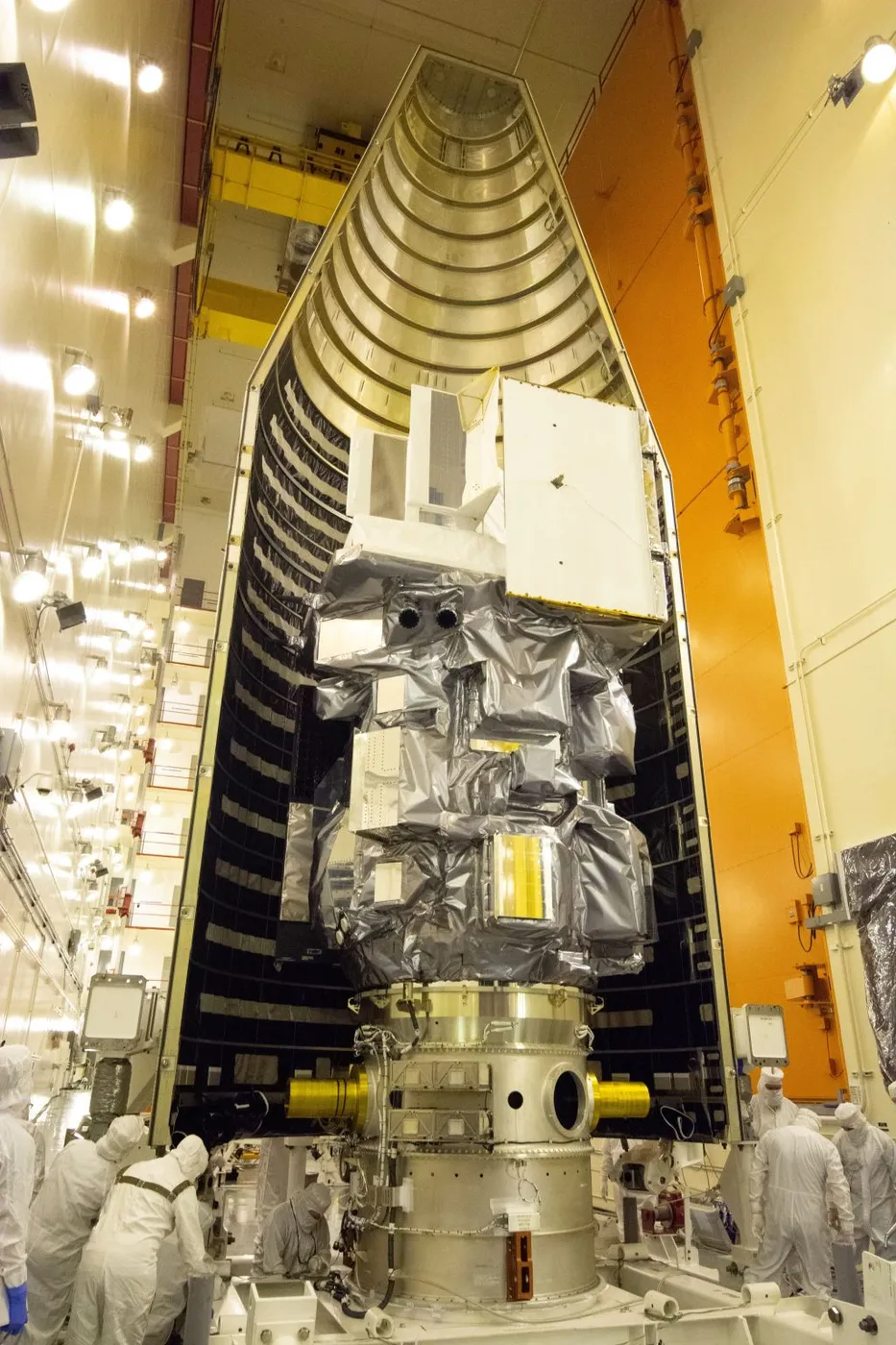 A satellite mounted on its adapter during fairing encapsulation, the fairing half closing around it.